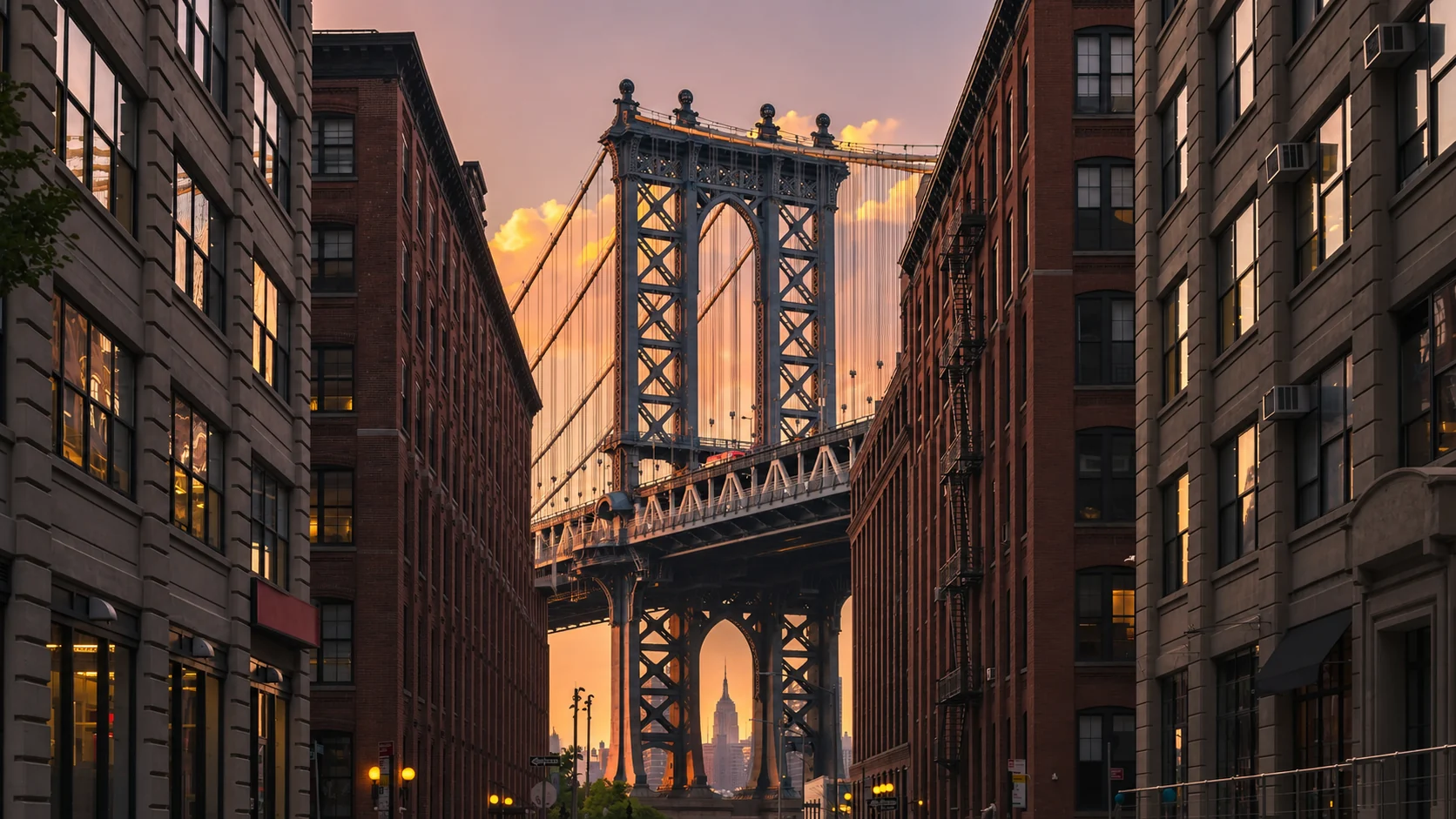 Warm evening light falls between New York brick buildings beneath the Manhattan Bridge.